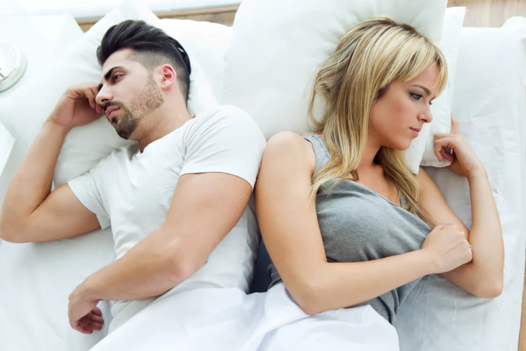 upset couple lying back to back in bed due to relationship issues